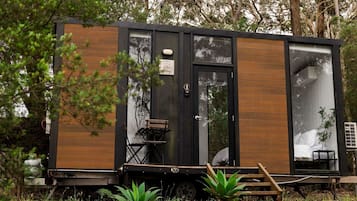 Une petite cabane moderne, avec une façade en bois, une porte coulissante et une petite terrasse.