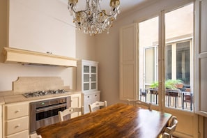 A kitchen with a wooden table, white cabinets, a gas stove, and a chandelier. - Tuscan Gold by MMega Homes and Villas (Florence)