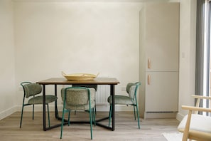 A dining area with a table and chairs, a basket on the table, and a white cabinet with a handle. - New 3 Bed House | Stafford | Private Parking (Stafford)