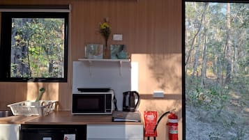 Una cocina con microondas, cafetera y extintor.