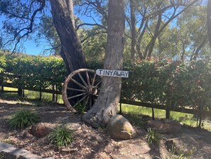 A rustic signpost with a vintage wagon wheel and a sign reading 'TINYAWAY' in a natural setting.