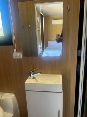 Ein Badezimmer mit Spiegel, Waschbecken und einem kleinen weißen Schrank.