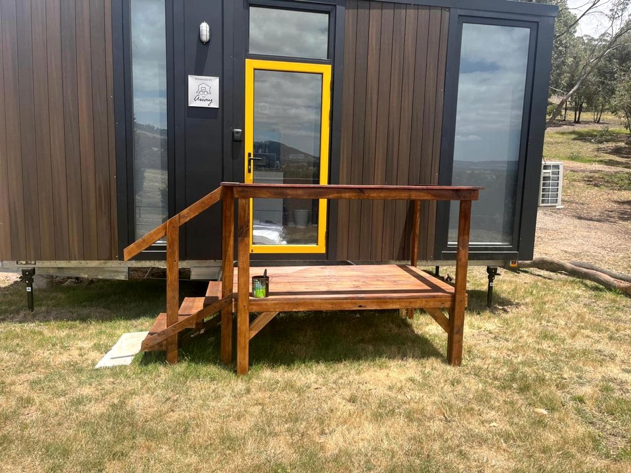 A modern cabin with a wooden deck and a yellow door.