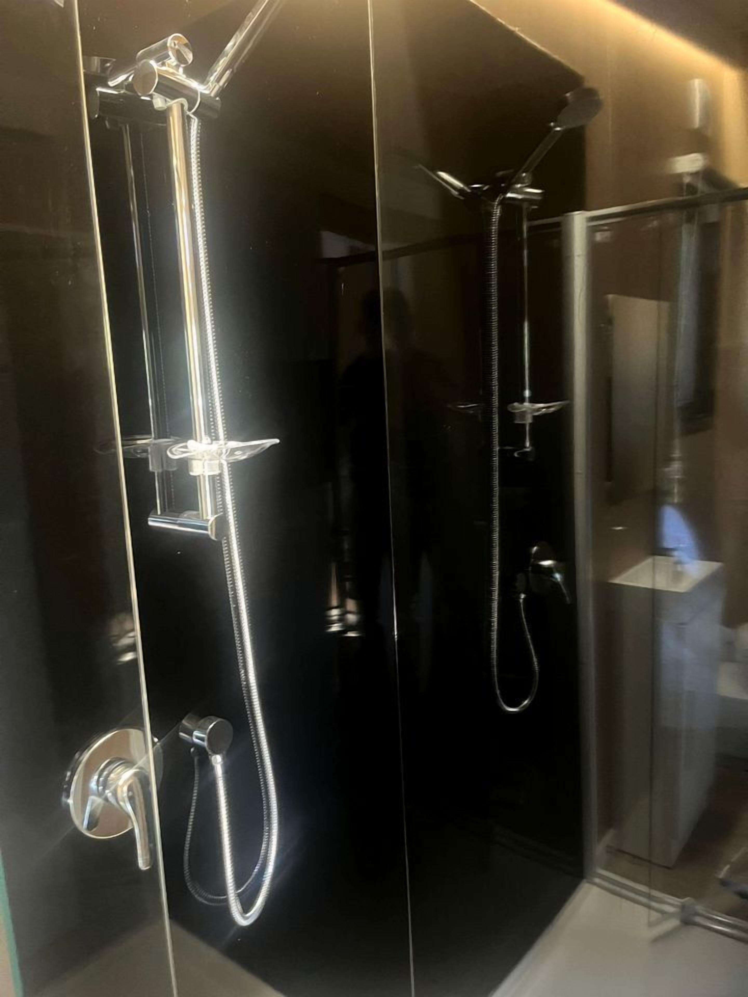 Eine Duschkabine mit verchromten Armaturen und einer Handbrause.