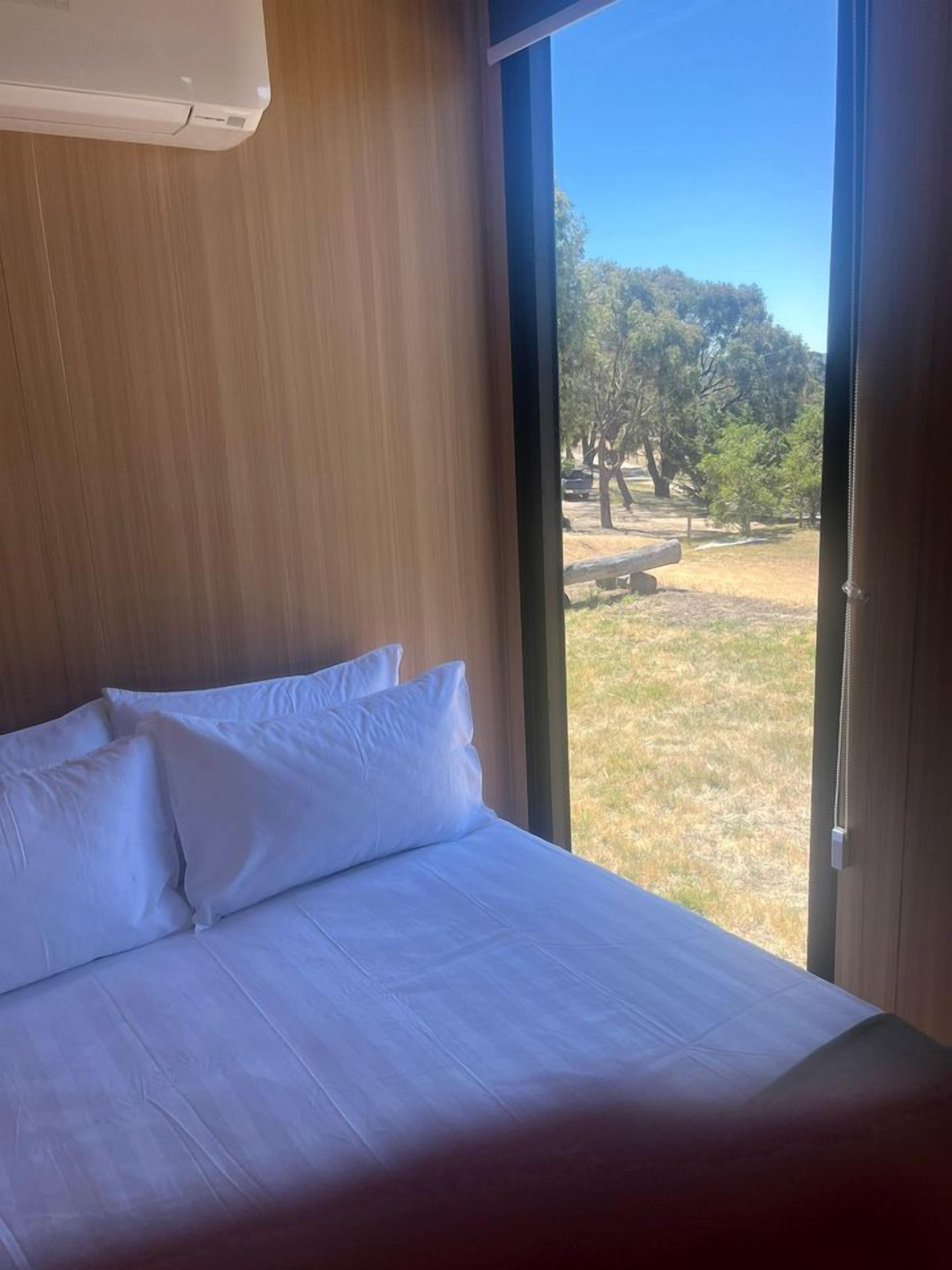 A bed with white linens in a room with a large window.