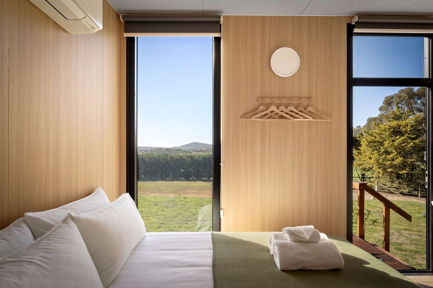 Habitación de hotel con una cama grande, vista al exterior y diseño de pared de madera.