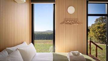 Habitación de hotel con una cama grande, vista al exterior y diseño de pared de madera.