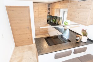 Una cocina moderna con armarios de madera, encimera negra y estufa integrada.