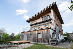 Ein mehrstöckiges Holzgebäude mit Balkonen, einer Treppe und einer Terrassenfläche.