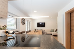 A modern living space with a dining area, a sofa, and a television mounted on the wall.