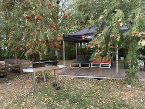 An outdoor patio area with a grill, seating, and a tent. - Apartment 'Gemütliche Mit Schwimmteich' with Shared Terrace, Shared Garden and Wi-Fi (Kemating)