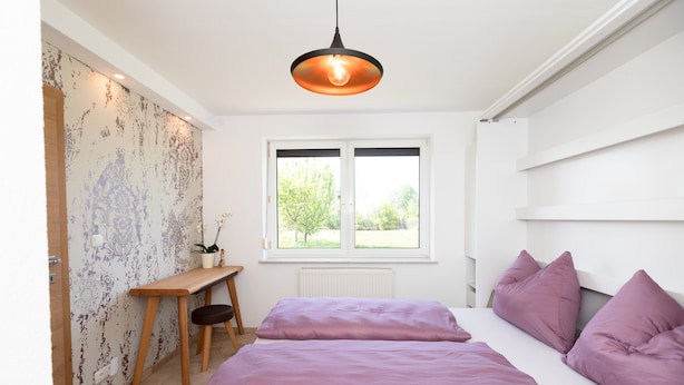 Un dormitorio con cama, escritorio y ventana.