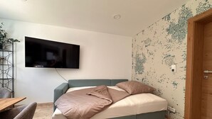 Un dormitorio moderno con cama, televisor montado en la pared y papel tapiz estampado.