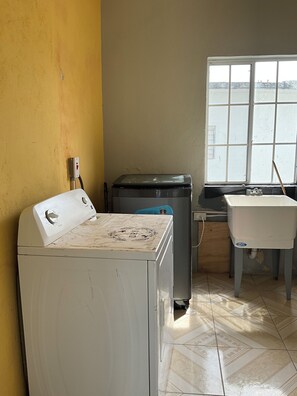 A room with a washing machine, a sink, and a window with a view of a body of water. - Awesome 6-bedroom building with AC in St. Ann Parish (St. Ann Parish)