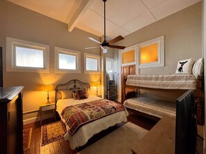 Ein Schlafzimmer mit einem Bett, Nachttischlampen, einem Deckenventilator, einem Stockbett und einem Fenster mit Blick.