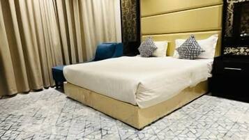 Una habitación de hotel con una cama grande, una mesita de noche, un armario y una ventana con cortinas.