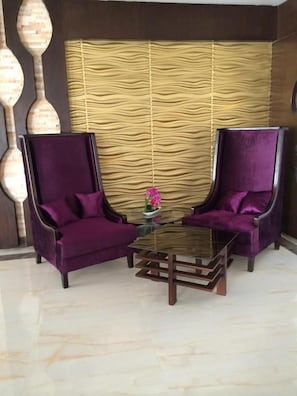 A room with two purple armchairs and a glass coffee table. - Alrafahya Crown (Riyadh)