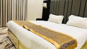 Una habitación de hotel con una cama grande, una mesita de noche, un equipo de aire acondicionado y una ventana con cortinas.