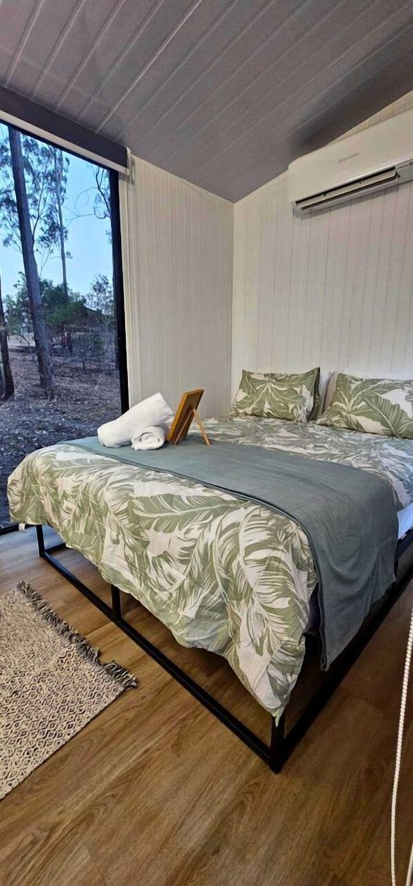 A bedroom with a bed, a window, and a wall-mounted air conditioner.