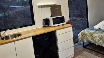 A compact bedroom with a bed, a bedside table, and a window.