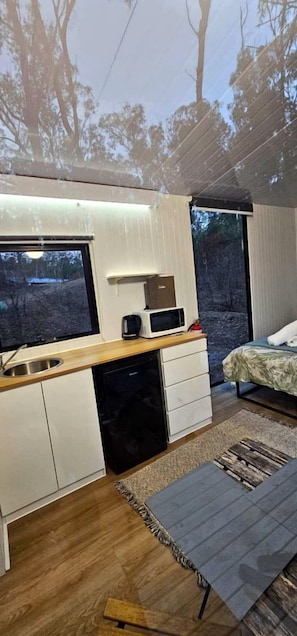 Une chambre à coucher de taille réduite, comprenant un lit, une table de chevet et une fenêtre.
