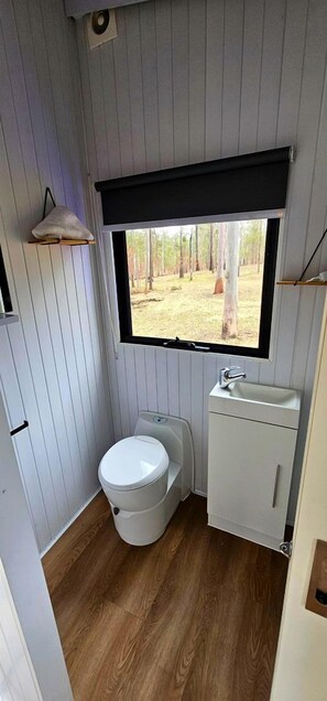 Une petite salle de bain comprenant des toilettes, un lavabo et une fenêtre.