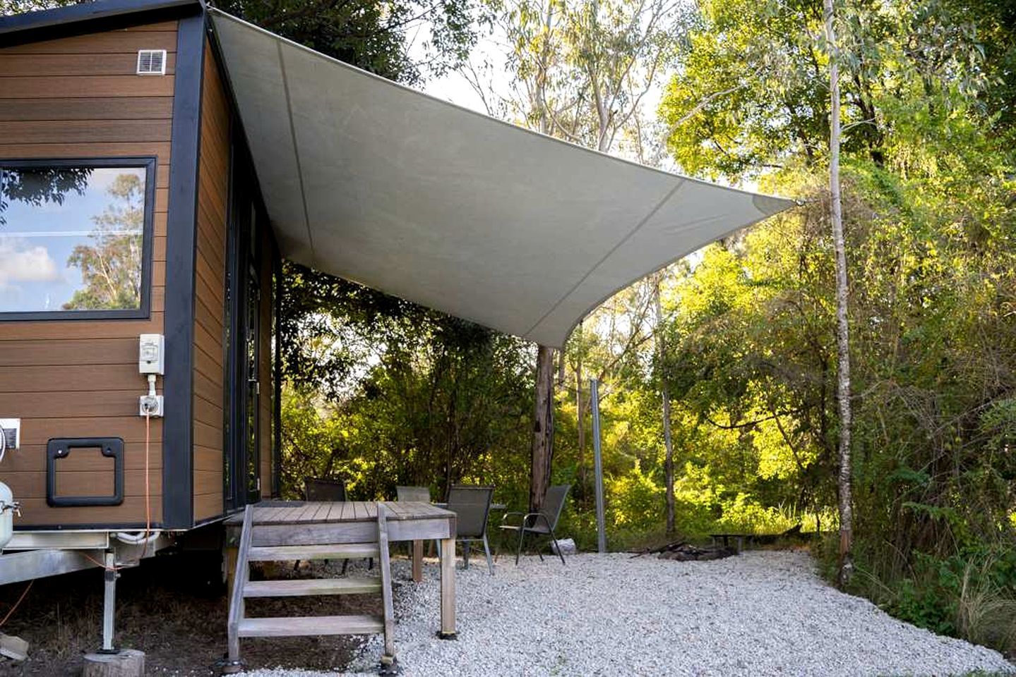 Une cabane en bois dotée d’un patio couvert, de meubles d’extérieur et d’un sol en gravier.