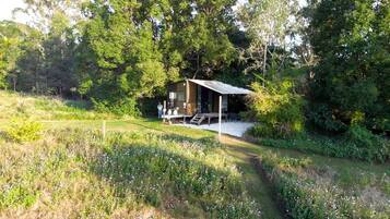 Una cabaña con terraza, rodeada de abundante vegetación y árboles.