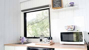 A kitchen with a window, a microwave, a sink, and a welcome sign.