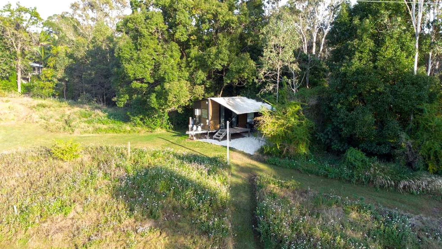 Un chalet isolé, doté d’une véranda et entouré d’une forêt dense.