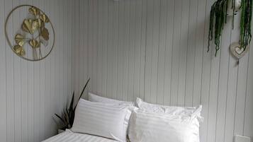 A bedroom with a bed, a wall-mounted air conditioner, a decorative wall piece, and a hanging plant.