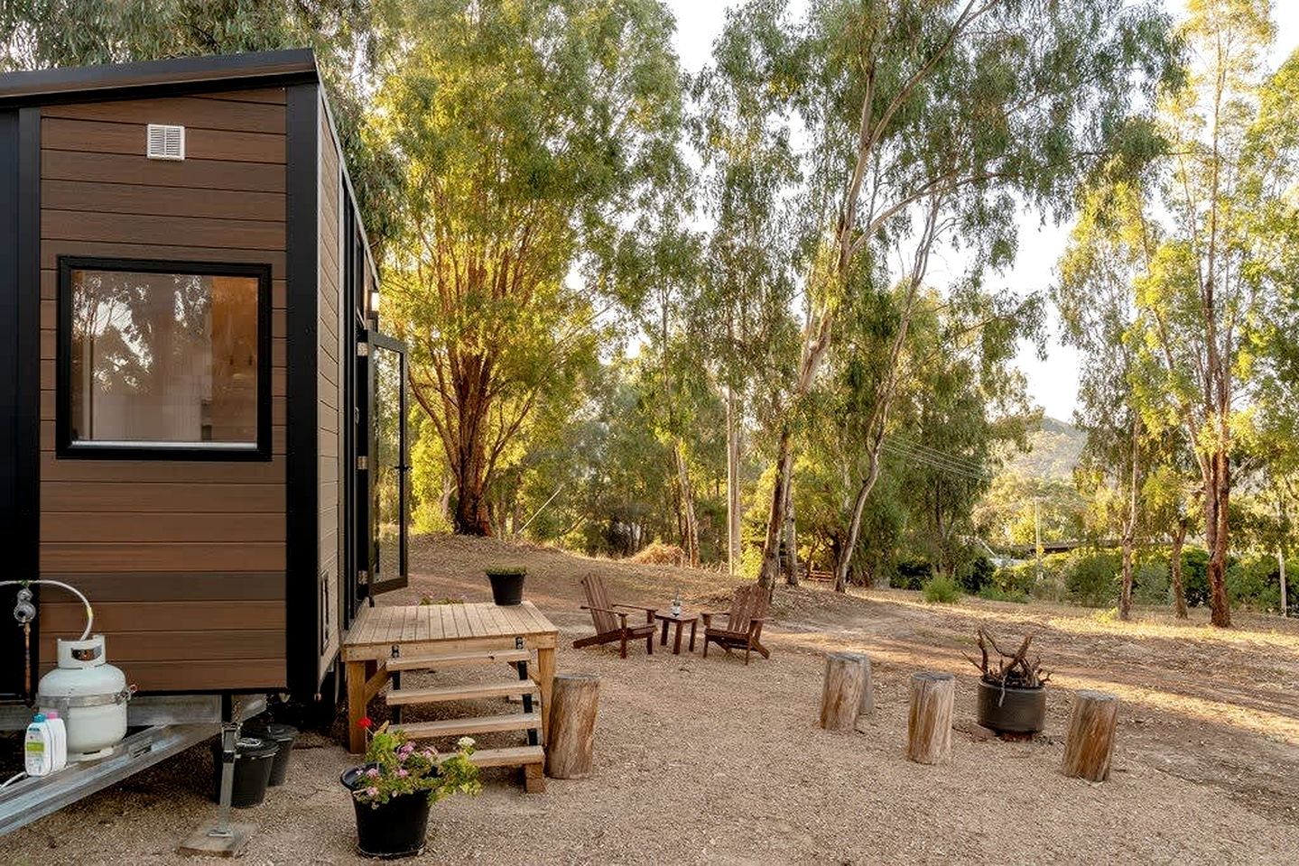 Une petite cabane dotée d’une terrasse en bois, de meubles d’extérieur et d’un sol en gravier.