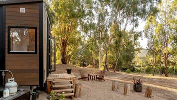 Une petite cabane dotée d’une terrasse en bois, de meubles d’extérieur et d’un sol en gravier.