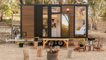 Een moderne, compacte stacaravan met een keukenhoek, een slaapgedeelte met een bed en een eethoek.
