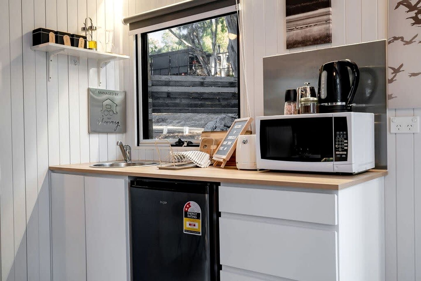 A compact kitchen with a built-in microwave, a coffee maker, and a dishwasher.