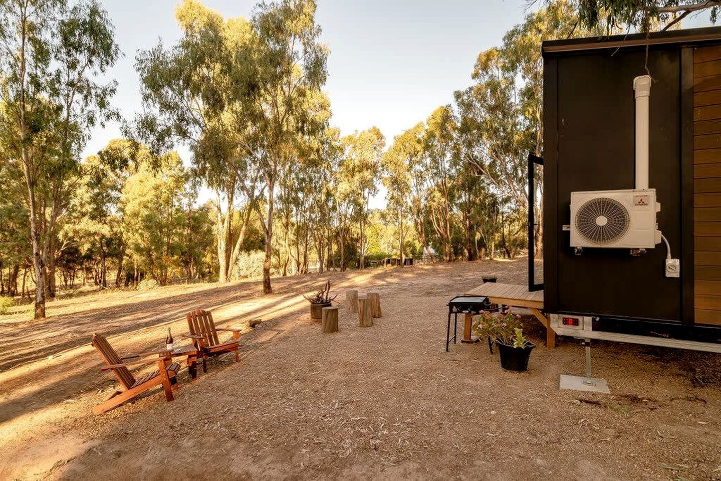 Een camping met een houten terras, een barbecue en een mobiele airconditioning.