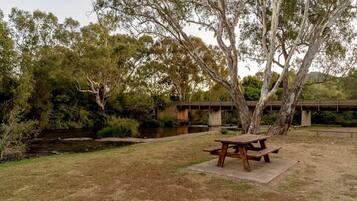 A picnic table in a park with a bridge in the background.