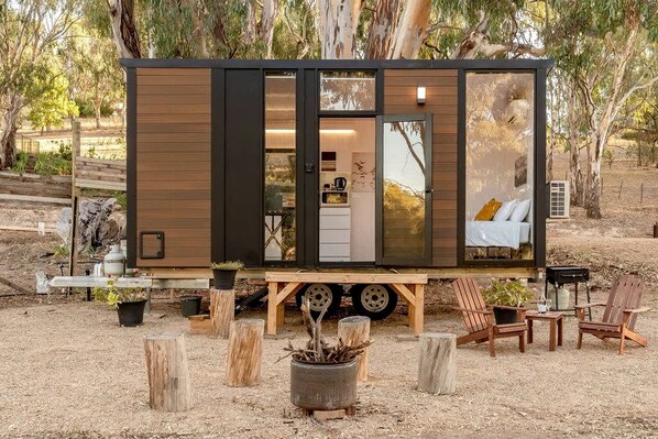 Una casa móvil moderna y compacta con cocina, zona de descanso con cama y espacio para comer.