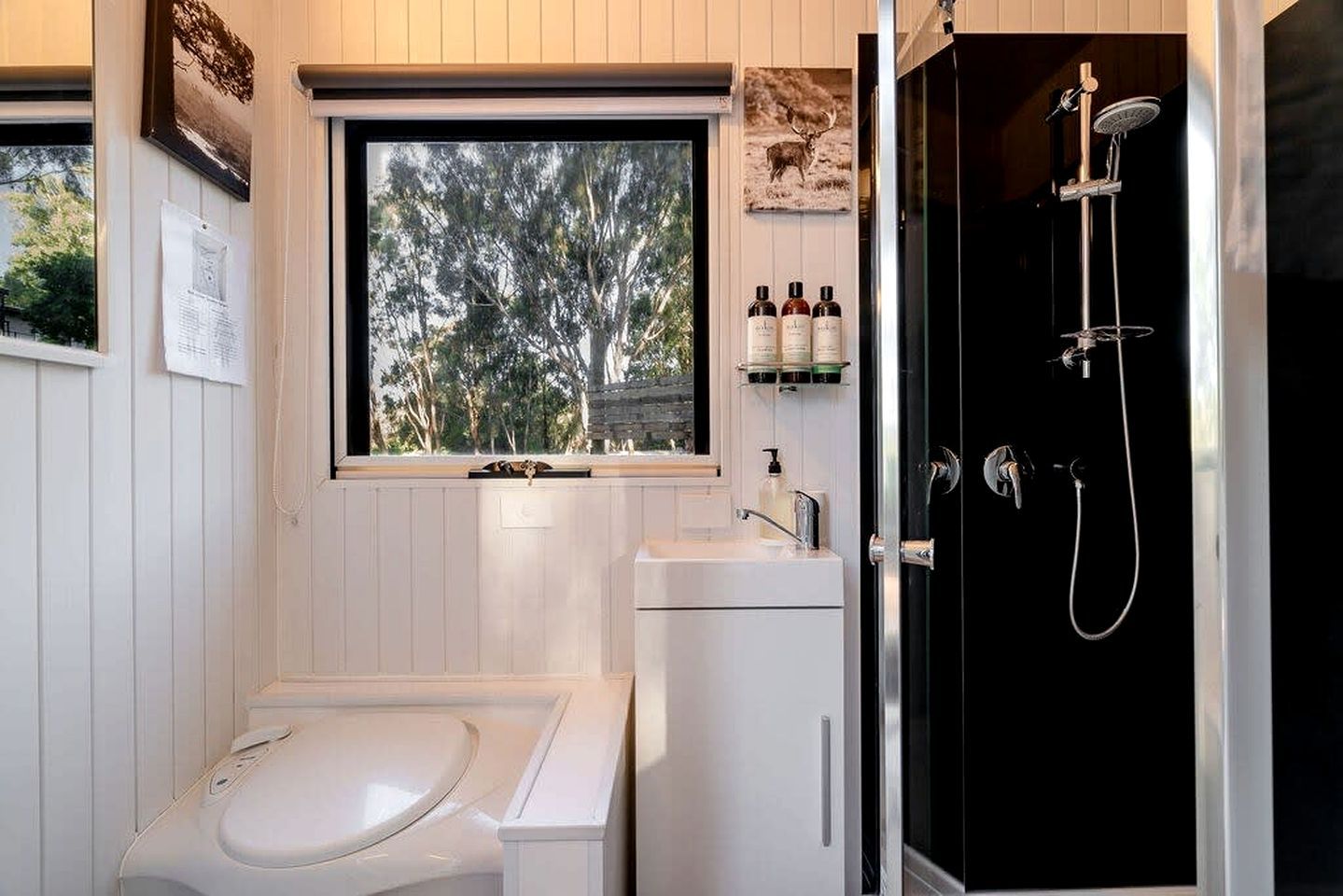 A bathroom with a bathtub, a sink, and a shower. There is a window with a view of trees.