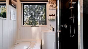 A bathroom with a bathtub, a sink, and a shower. There is a window with a view of trees.