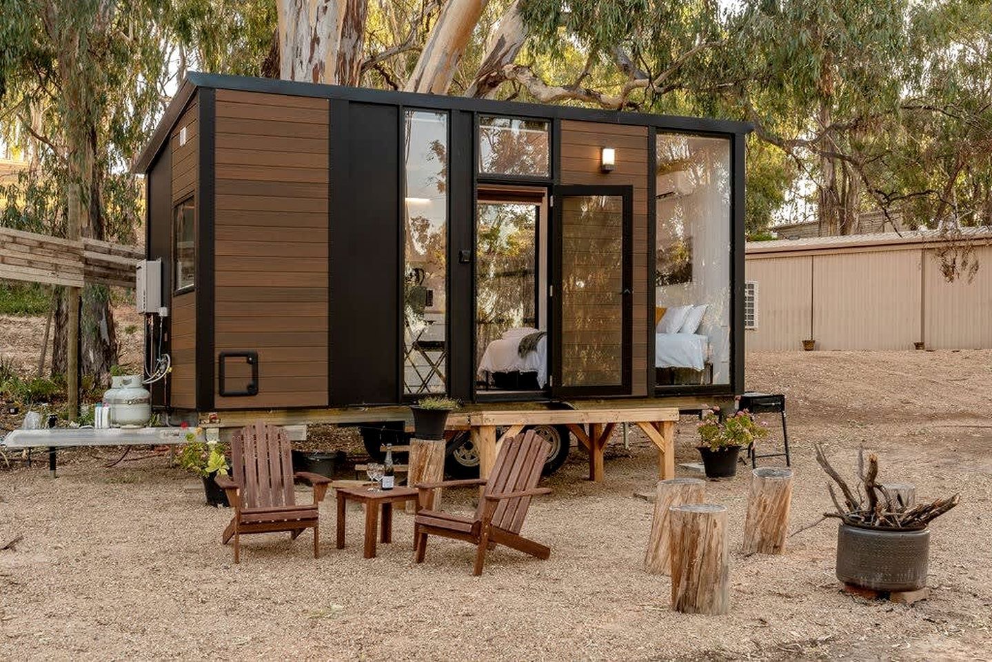 Une cabane moderne et compacte dotée d’une grande porte-fenêtre coulissante, d’une terrasse en bois et d’un espace salon extérieur.
