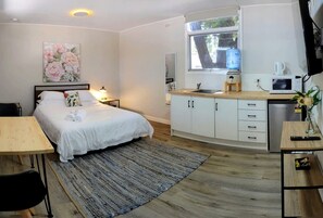 A bedroom with a bed, bedside table, lamp, and a painting. - Grampians Wine Country Glamping, Perfect for a Weekend Adventure (Dadswells Bridge)