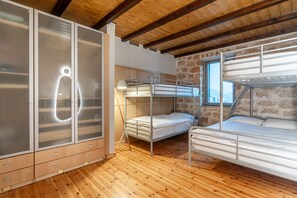 Une petite pièce avec des lits superposés, une armoire et une fenêtre.