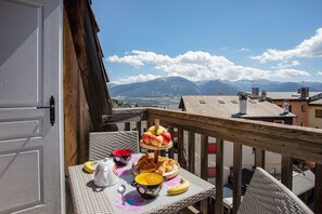 Un balcón con una mesa dispuesta para el desayuno, con vistas a un paisaje montañoso.