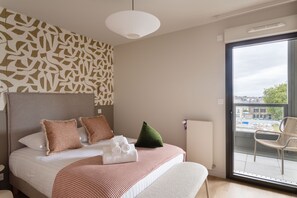 A hotel room with a bed, pillows, a blanket, a radiator, and a view of the outside. - L'Écrin du Homard Bleu - Plein centre de Dinard (Dinard)