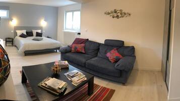 Een moderne woonkamer met een bed, een bank, een salontafel en een decoratieve vaas.