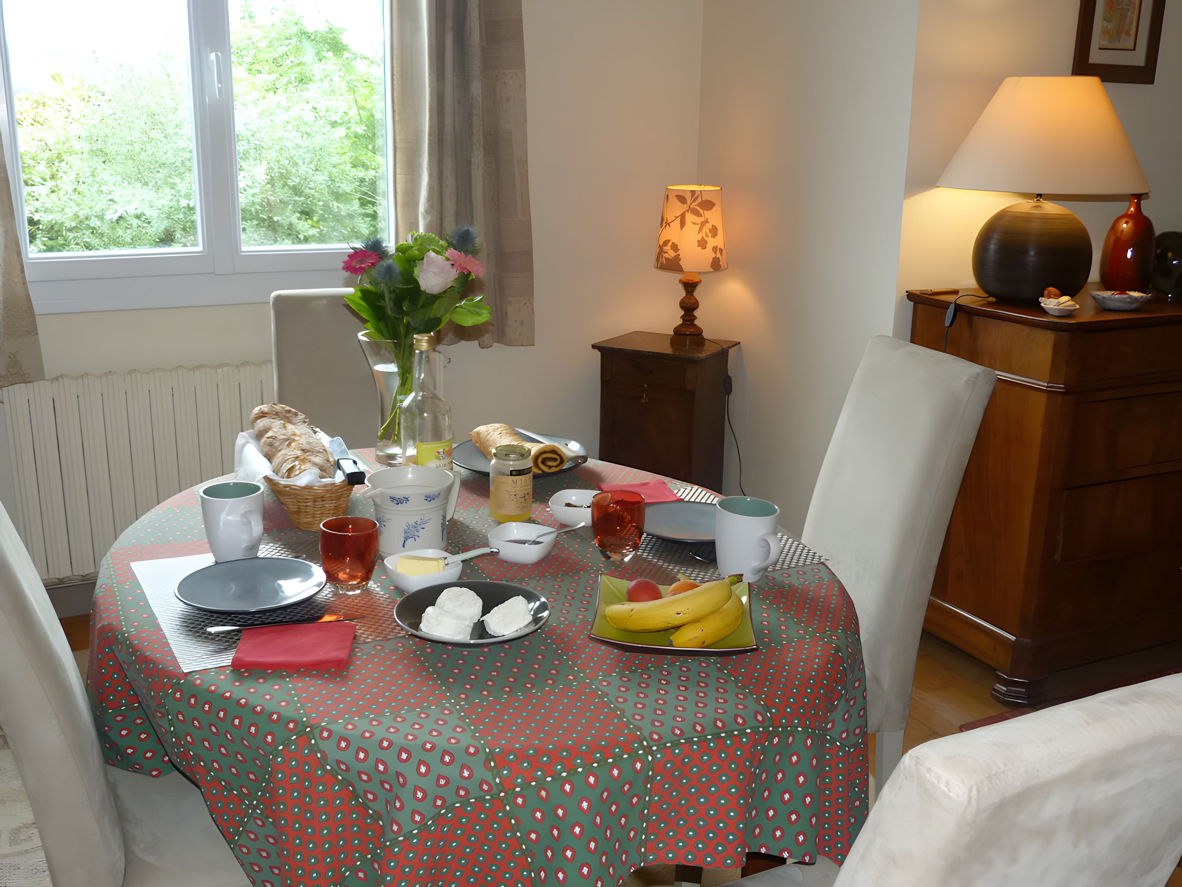 A dining table with a polka-dotted tablecloth, various food items, a vase with flowers, and a lamp.