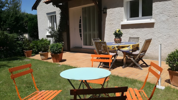 Une terrasse extérieure avec une table et des chaises, entourée de plantes en pot.