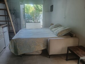 Ein Schlafzimmer mit einem Bett, einem kleinen Tisch, einer Bank, einem Kleiderschrank und einer Treppe.