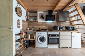 Eine kleine Küche mit Waschmaschine, Backofen und Mikrowelle.